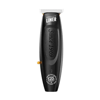 Máquina de acabamento da marca GA.MA Italy, da linha Absolute Liner. O produto tem um design preto fosco com detalhes em laranja. A embalagem é um aparador de plástico alongado com uma lâmina de corte na extremidade.