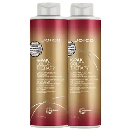 A imagem mostra dois frascos de shampoo e condicionador da  marca Joico. Os frascos têm formato cilíndrico e são feitos de plástico branco na parte superior e vermelho degradê para dourado na parte inferior.