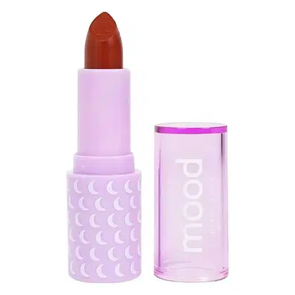 Batom da marca Ruby Rose. O batom possui uma embalagem lilás com um padrão de luas brancas, e a tampa do batom é de uma cor vermelha alaranjada. O rótulo do produto exibe claramente a marca "Ruby Rose" em letras brancas.