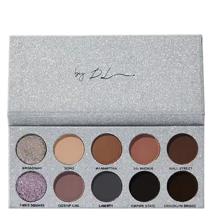 Paleta de sombras de olhos compacta com embalagem retangular de aparência glitter prateada. A caixa contém 10 sombras prensadas em tons neutros e profundos, variando do bege claro ao marrom escuro.