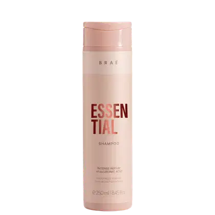 Frasco rosa claro de shampoo da marca Braé, com rótulo em vermelho destacando o nome "Essential" e informações sobre o produto, como "Intense Repair Hyaluronic Acid".