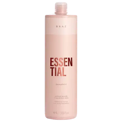 Frasco de shampoo da marca Braé, na cor rosa claro, com rótulo destacando o nome "Essential" e informações sobre o produto, como "Intense Repair" e "Hyaluronic Acid".