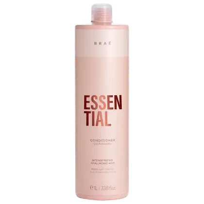 Frasco rosa claro de condicionador da marca Braé, com rótulo em vermelho destacando "ESSENTIAL" e informações sobre o produto, como "Intense Repair Hyaluronic Acid".