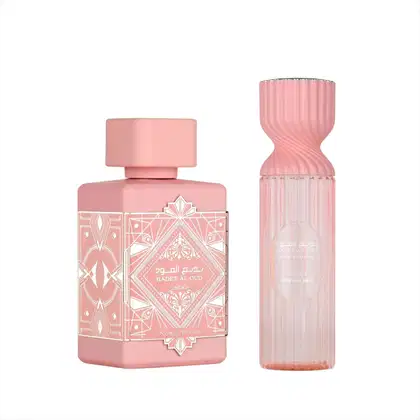 Dois frascos de perfume da marca Lattafa Perfumes, em tons de rosa, com design decorativo e rótulos em árabe. O frasco maior possui formato ondulado, enquanto o menor tem formato cilíndrico.