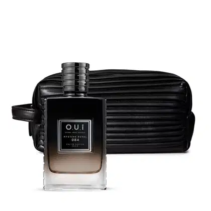 A imagem mostra um frasco de perfume masculino da coleção "Mystère Royal 084" em um tom âmbar escuro. Ao lado, há uma necessaire ou estojo em material sintético texturizado com listras na cor preta.