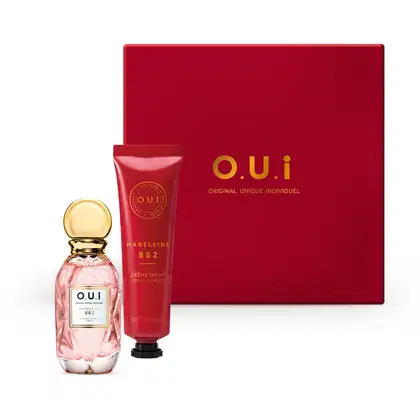 A imagem mostra uma caixa vermelha com o nome da marca em letras douradas, um frasco com eau de parfum na cor rosa e um tubo vermelho com creme hidratante para as mãos.
