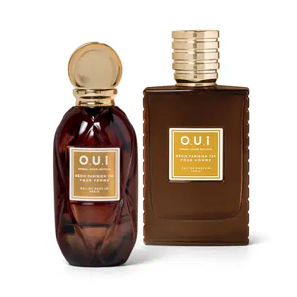 Dois itens de perfumaria da marca O.U.i em embalagens de vidro e metal dourado. São frascos de vidro marrom escuro com tampa dourada. 