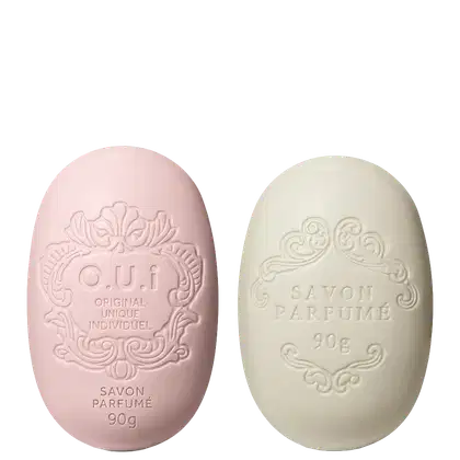 Dois sabonetes O.U.i em formato oval com relevos decorativos. À esquerda, sabonete rosa com inscrição "O.U.i Original Unique Individuel" e "Savon Parfumé 90g". À direita, sabonete bege com texto "Savon Parfumé 90g".