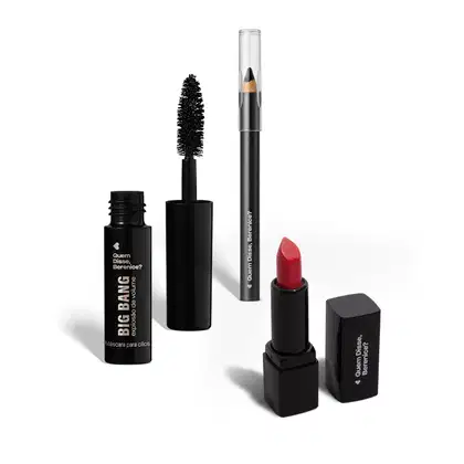 A imagem mostra três produtos de maquiagem da marca Quem Disse, Berenice?. Um rímel preto em embalagem cilíndrica com um aplicador de cerdas pretas espessas. Um lápis preto para olhos. E um batom bala vermelho em uma embalagem preta.