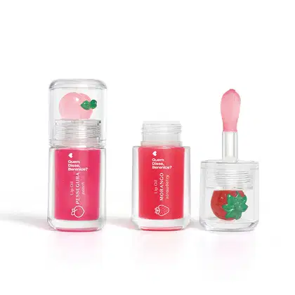 Imagem do Combo Lip Oil Quem Disse, Berenice? com um produto na cor Vermelho Morango em tonalidade vermelha e morango decorativo e Rosa Fúcsia Pessegura em tonalidade rosa claro e pêssego decorativo. As embalagens são transparentes com aplicador. macio.