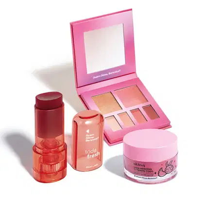 Paleta de maquiagem, blush em tom bordô e hidratante labial da marca Quem Disse, Berenice?. Embalagens em tons de rosa e vermelho com textos e logotipos da marca.