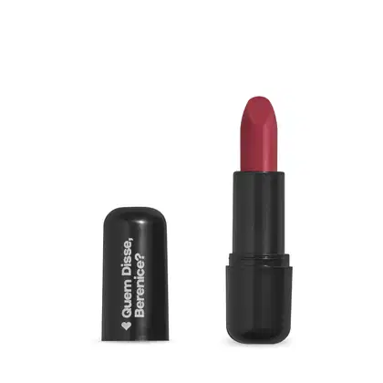 O produto apresentado na imagem é um batom da marca Quem Disse, Berenice?. O batom possui uma embalagem preta com o logotipo da marca em branco. A cor do batom é um tom de rosa avermelhado.