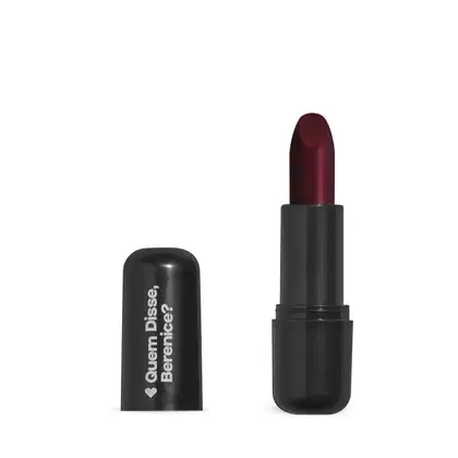 O produto apresentado na imagem é um batom da marca Quem Disse, Berenice?. O batom possui uma embalagem preta e o produto em si é de cor vinho escuro. O rótulo na embalagem apresenta o nome da marca "Quem Disse, Berenice?" em letras brancas.