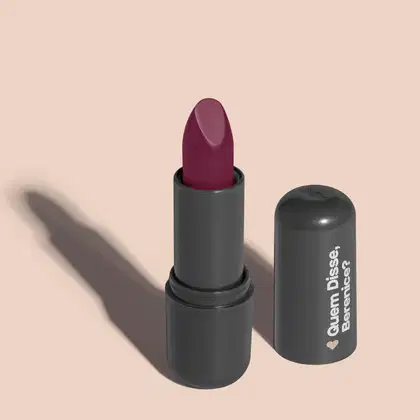 O produto apresentado na imagem é um batom da marca Quem Disse, Berenice?. O batom possui uma embalagem preta e o produto em si é de cor vinho escuro. O rótulo da embalagem apresenta o nome da marca "Quem Disse, Berenice?" em letras brancas.