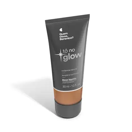 O produto apresentado é uma base líquida da marca Tô no Glow, com embalagem em tubo plástico de cor cinza escura. O rótulo exibe o nome da marca e o texto "Radiância natural, leveza e conforto" em letras brancas.