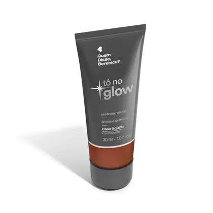 O produto apresentado é uma base líquida da marca Tô no Glow, com embalagem em tubo plástico de cor cinza escura. O rótulo exibe o nome da marca e o texto "Radiância natural, leveza e conforto" em letras brancas.