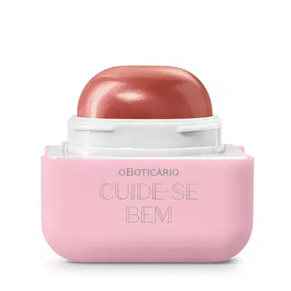 Protetor labial da marca Cuide-se Bem, com embalagem quadrada de plástico em tons de rosa claro e branco. O produto está aberto e vemos a bala em formato de semicírculo de tom avermelhado. O logo está gravado em cinza na embalagem. 