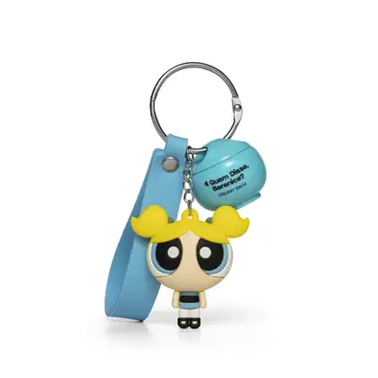 Chaveiro em formato da personagem Florzinha das Meninas Superpoderosas, com vestido azul e cabelo amarelo, preso a um produto da marca Quem Disse, Berenice?.