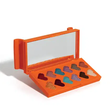 Paleta laranja em forma de sofá com compartimentos em formato de coração, contendo sombras de olho em tons de marrom, dourado e turquesa. A caixa possui uma tampa com encaixes. 