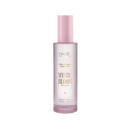 Frasco de spray perfumado Mystic Bloom da marca Skelt, com embalagem rosa e branca, contendo texto em dourado indicando o nome do produto e a fragrância.
