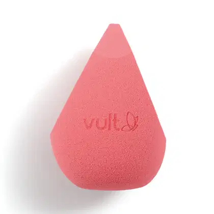 Esponja de maquiagem triangular de cor rosa vibrante. Possui textura porosa e macia. Na superfície, está impresso em decalque o logotipo Vult. O produto tem formato cônico, com uma das pontas mais afilada e apresenta um acabamento fosco e uniforme.
