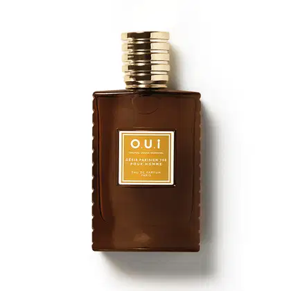 Frasco de item de perfumaria da marca O.U.i. com formato retangular, tampa dourada e rótulo com texto em amarelo e marrom sobre fundo marrom escuro.