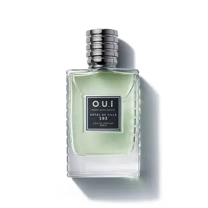 Frasco de item de perfumaria da marca O.U.i, com formato retangular, tampa prateada e rótulo preto com texto "HOTEL DE VILLE 193" em fundo verde claro.