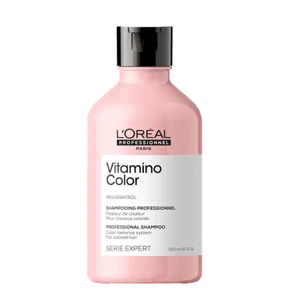 Frasco de plástico rosa com tampa preta. Rótulo com texto "L'OREAL PROFESSIONNEL PARIS Vitamino Color" e "SHAMPOOING PROFESSIONNEL". Produto de cuidados capilares para cabelos coloridos.