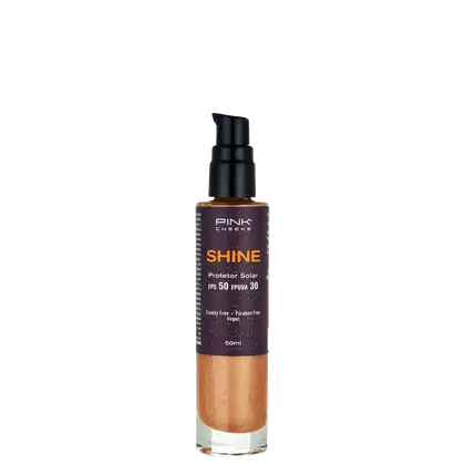 Frasco de protetor solar da marca Pink Cheeks, com o nome "Shine" e informações sobre FPS 50 e FPUVA 30. O produto é de cor laranja e possui um rótulo preto com detalhes em branco. A embalagem é de plástico e possui um aplicador tipo bomba.