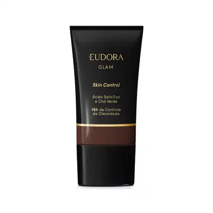 Embalagem plástica preta com detalhes em preto e dourado. Rótulo indica que é um Skin Control com ácido salicílico e chá verde, proporcionando 16 horas de controle da oleosidade. A cor da base é tom marrom escuro.