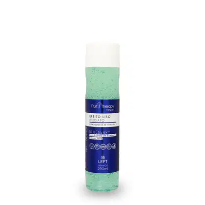 A imagem mostra um frasco transparente com rótulo azul e tampa branca de 290ml do shampoo da linha Fruit Therapy Vegan Blueberry, onde é possível ver o conteúdo esverdeado por dentro. O design traz informações sobre benefícios e composição.