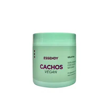 O produto apresentado é um pote de gelatina Essendy Cachos Vegan. A embalagem é verde clara, com o nome da marca "Essendy" e o produto "Cachos Vegan" escrito em roxo. O recipiente possui um formato cilíndrico e uma tampa.