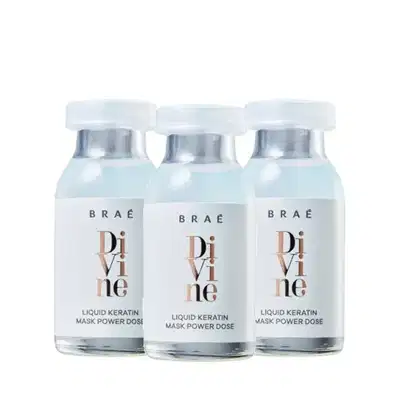 Três frascos de vidro transparentes contendo um líquido branco, com tampas prateadas e rótulos com o nome da marca "Braé" e o produto "Divine Liquid Keratin Mask Power Dose".