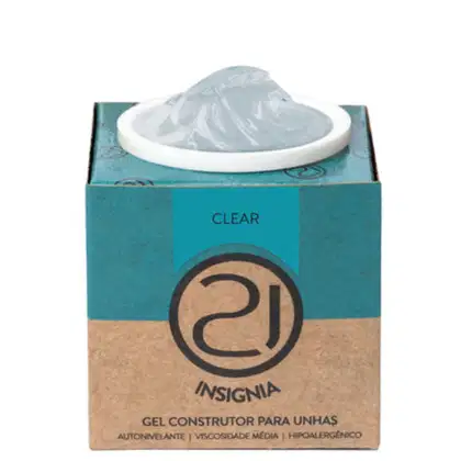 A imagem mostra o gel construtor para unhas em uma embalagem retangular de papelão na cor turquesa e bege, com o logotipo da marca em preto. Contém um pote branco com o produto gel transparente aparecendo no topo.