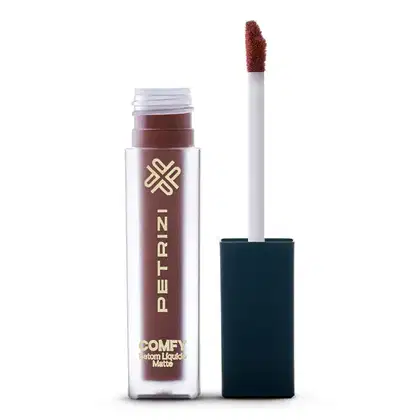 O produto é um batom líquido mate da marca Petrizi Makeup, com embalagem branca e detalhes dourados. O recipiente é cilíndrico e possui um aplicador de ponta macia na cor marrom.