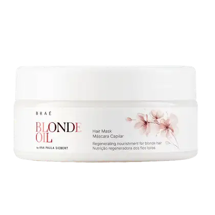 Embalagem branca com rótulo da linha Braé Blonde Oil, contendo máscara capilar regeneradora para cabelos loiros. Apresenta flores rosa na embalagem, indicando o aroma e propriedades do produto.
