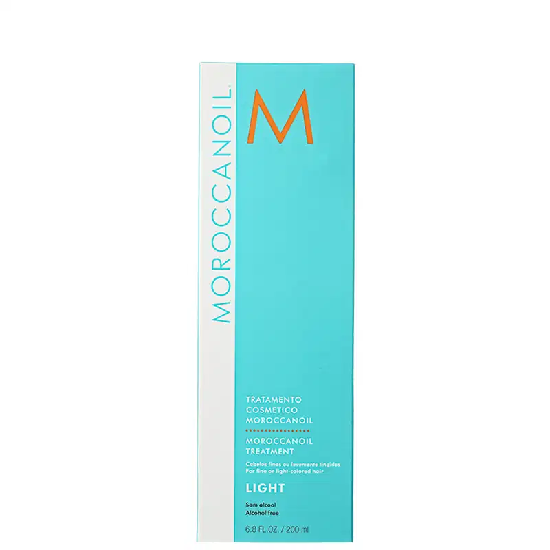 A imagem mostra a caixa do produtos Moroccanoil Treatment Light. Embalagem retangular de cor azul clara e branca. Logotipo laranja "M" em destaque.