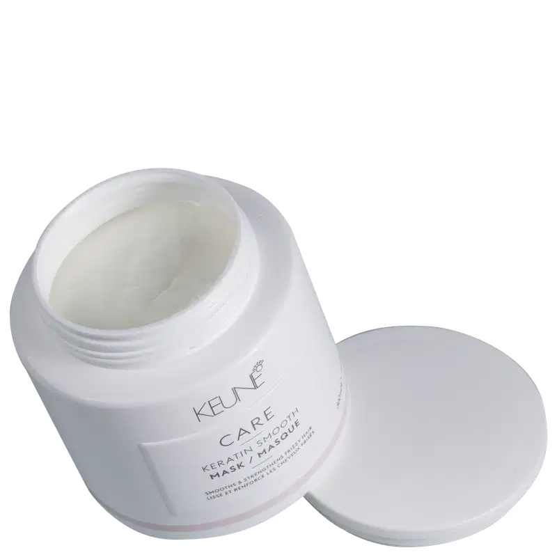 Recipiente branco de produto de tratamento capilar da marca Keune, com rótulo destacado em fundo preto, sugerindo um ambiente de cuidados pessoais e beleza.