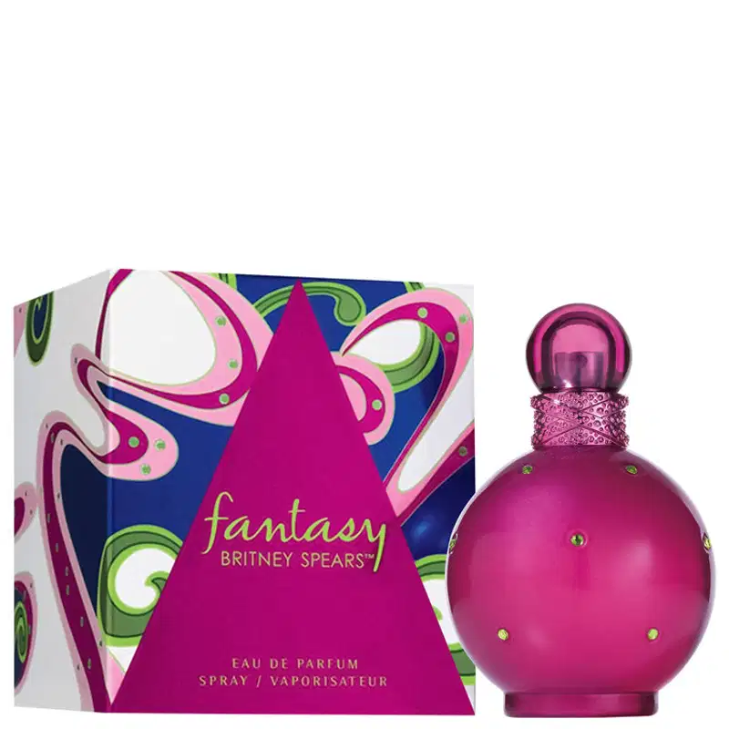 Perfume Fantasy da marca Britney Spears. Frasco de vidro arredondado na cor rosa vibrante com detalhes de strass. Caixa retangular com design abstrato em tons de rosa, azul e verde, exibindo o nome "Fantasy" e a marca Britney Spears em letras douradas.