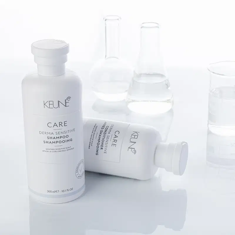 Frasco branco de condicionador Keune Care Derma Sensitive, com 250 ml de capacidade. O rótulo apresenta o nome da marca e do produto, bem como informações sobre sua função de acalmar o couro cabeludo sensível.