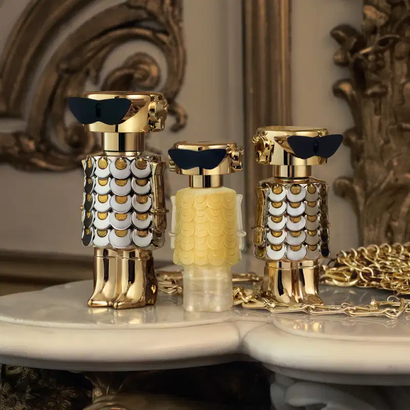 Frasco de perfume dourado e prateado com design escamado, evocando uma aparência luxuosa e sofisticada, típica da marca Paco Rabanne.