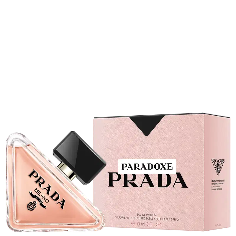 Frasco de perfume Prada com design triangular em vidro transparente, contendo líquido de cor rosa clara. O rótulo preto destaca o nome da marca "PRADA" em letras brancas.