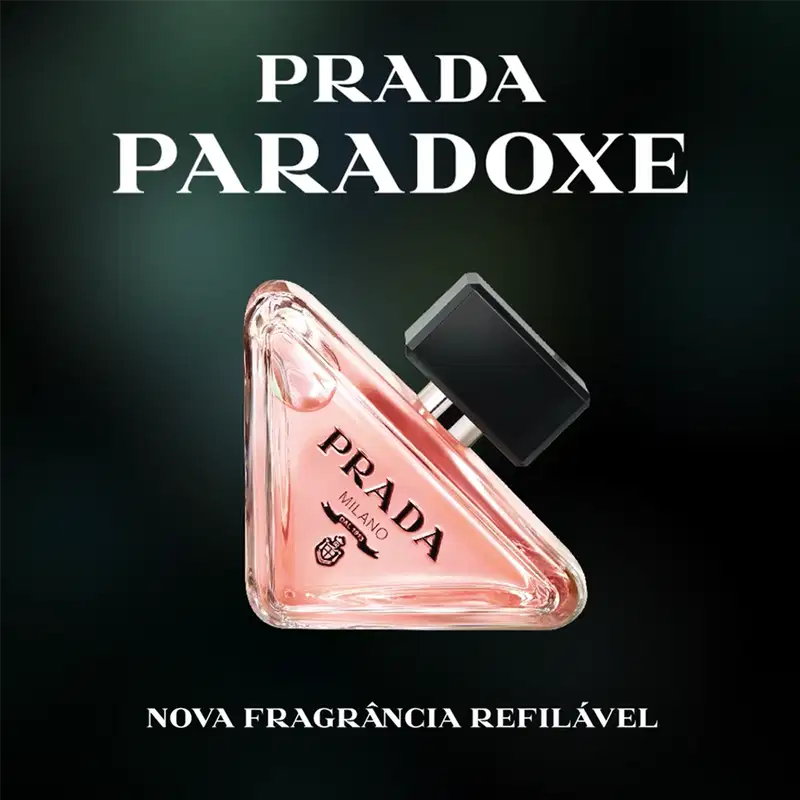 Frasco de perfume Prada com design triangular em vidro transparente, contendo líquido de cor rosa clara. O rótulo preto destaca o nome da marca "PRADA" em letras brancas.