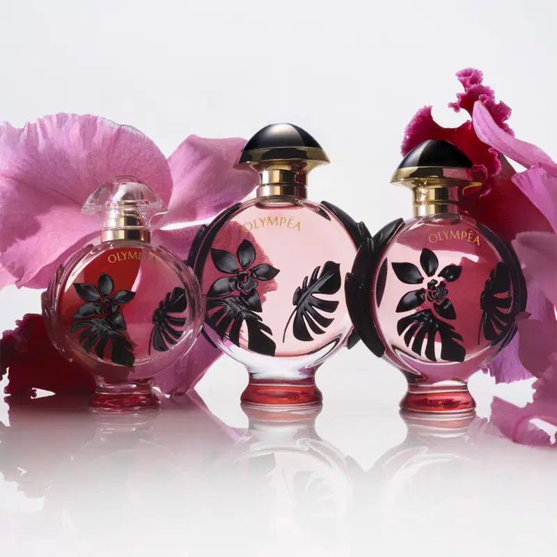 Três frascos de perfume Olympea da marca Paco Rabanne, com design elegante e floral em tons de rosa e preto, exibindo o nome da fragrância em destaque.