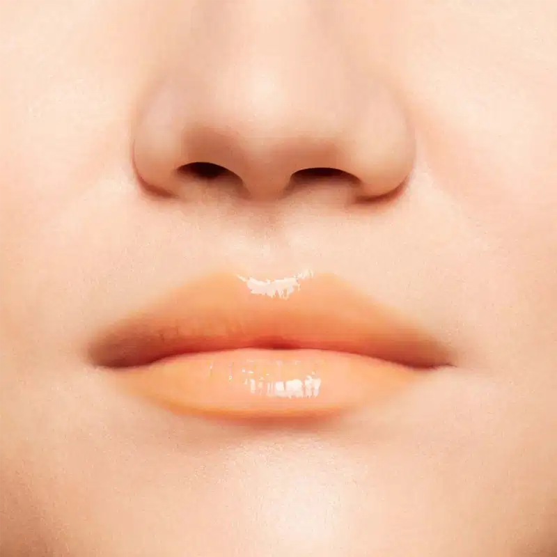 A imagem mostra a boca de uma mulher usando o balm.