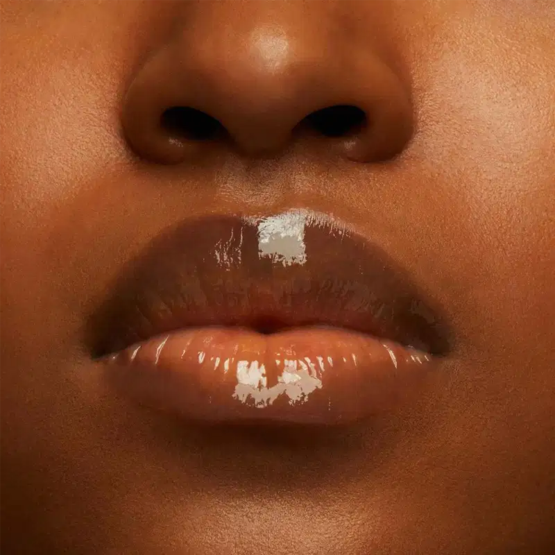 A imagem mostra a boca de uma mulher usando o balm.