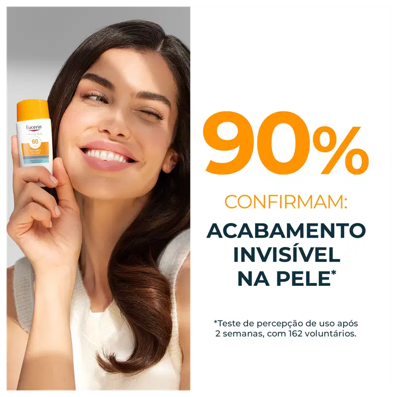 Uma mulher sorridente segurando um item de perfumaria da marca Eucerin com fator de proteção solar 60. O texto visível na embalagem confirma que o produto proporciona "acabamento invisível na pele" em 90% dos casos.