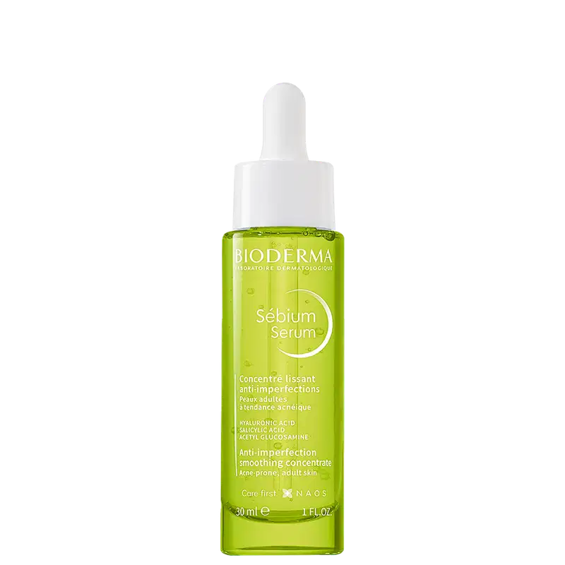 Frasco de vidro verde-limão com conta-gotas branco da linha Sebium Serum da Bioderma, um concentrado anti-imperfeições para peles adultas com tendência acneica. O rótulo destaca os principais ingredientes ativos, como ácido hialurônico e ácido salicílico.