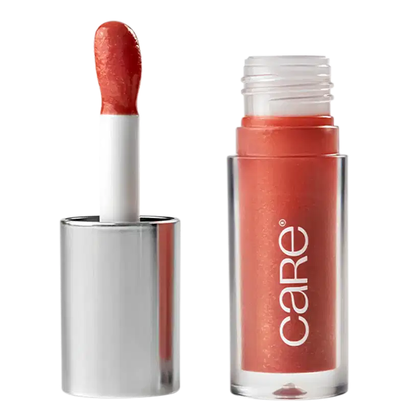 A imagem mostra o Lip Oil de Care Natural Beauty. Possui uma embalagem transparente de plástico, semelhante a um batom líquido. Possui cor rosa queimado e a embalagem apresenta o logotipo "Care" em letras brancas. A tampa prata com aplicador.