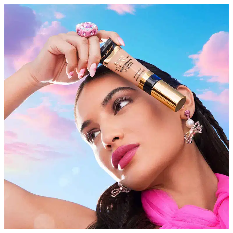 A imagem mostra uma mulher super produzida segurando uma embalagem da base próxima ao rosto.